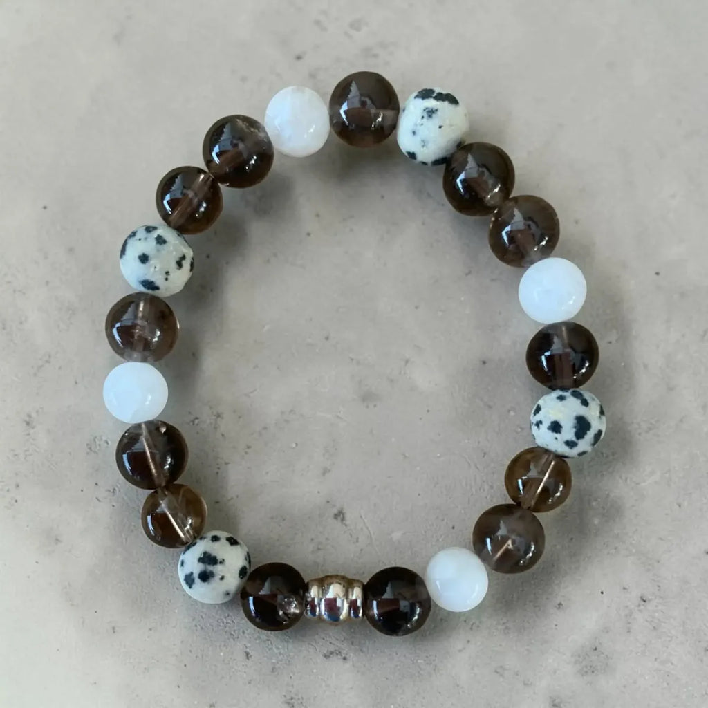 Calm and clear beaded bracelet with brown, white, and spotted beads on a beige background.