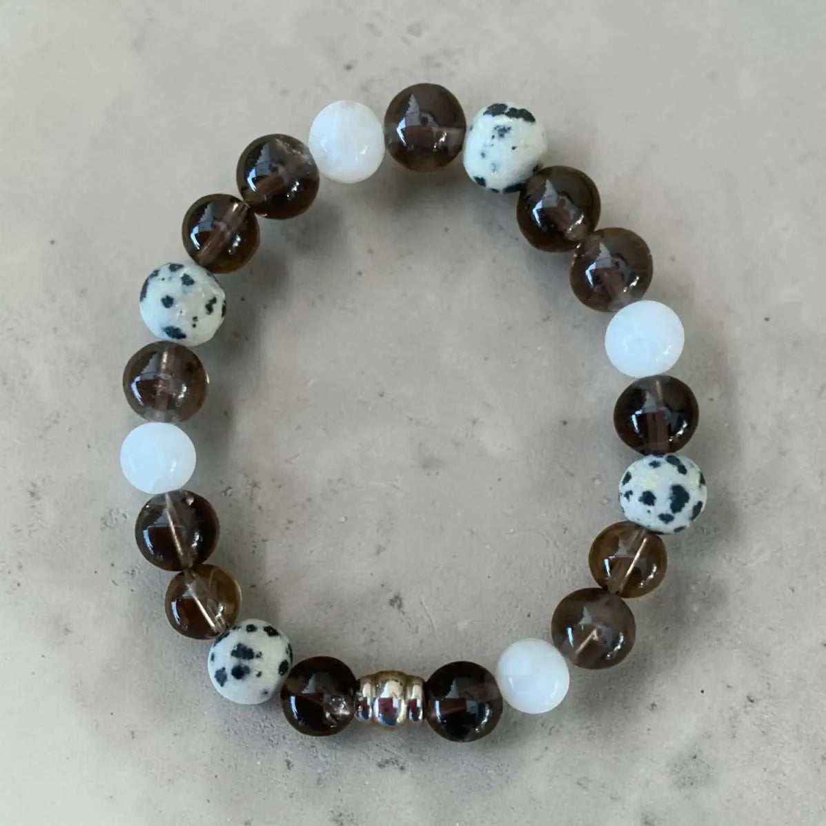 Calm and clear beaded bracelet with brown, white, and spotted beads on a beige background.