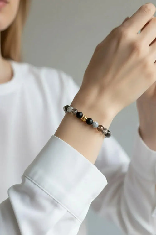 Person wearing a calm and clear beaded bracelet on a plain background.