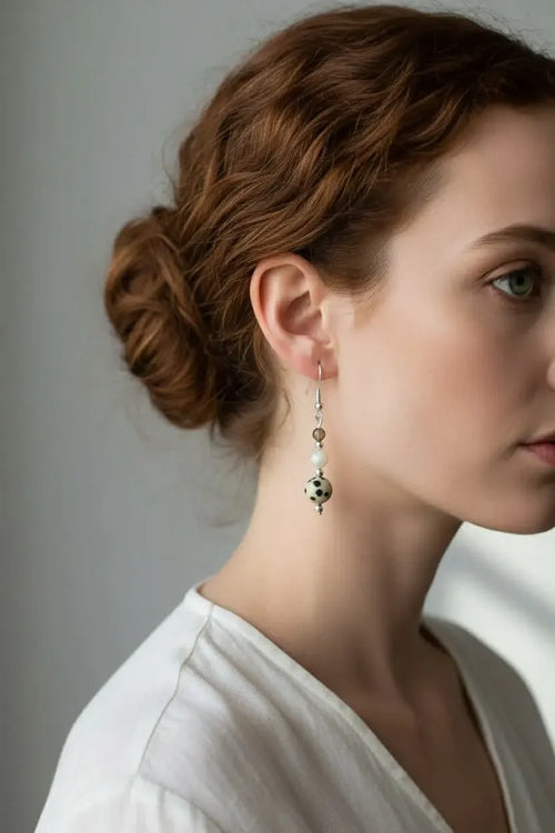 Close-up of a woman wearing calm and clear elegant earrings with a neutral background.