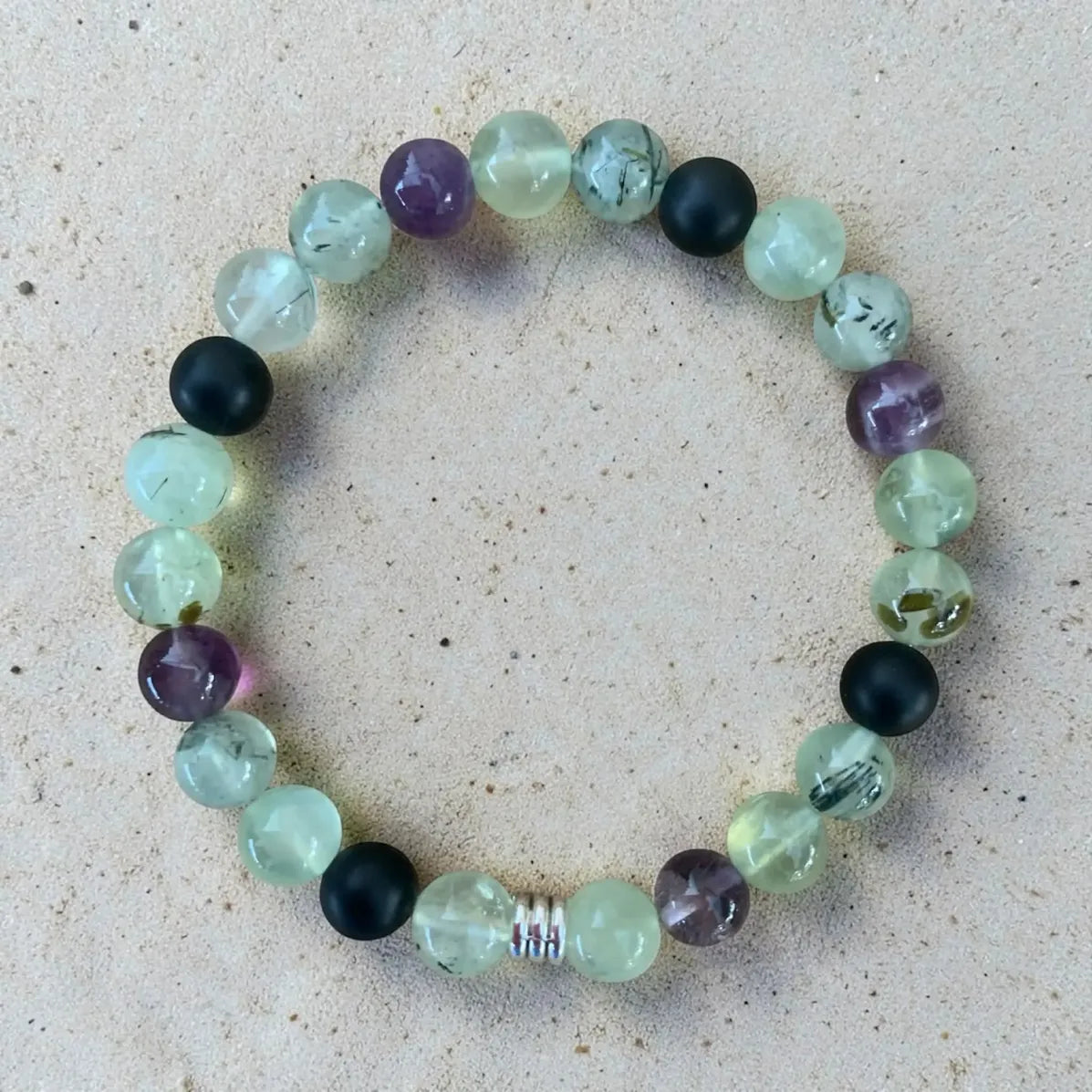 Multicolored beaded gentle boundaries bracelet on a sandy surface.
