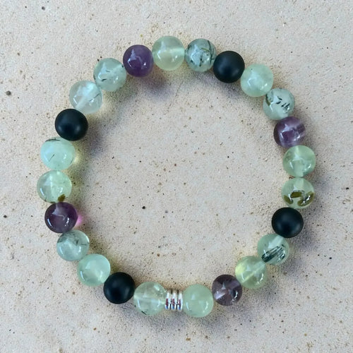 Multicolored beaded gentle boundaries bracelet on a sandy surface.