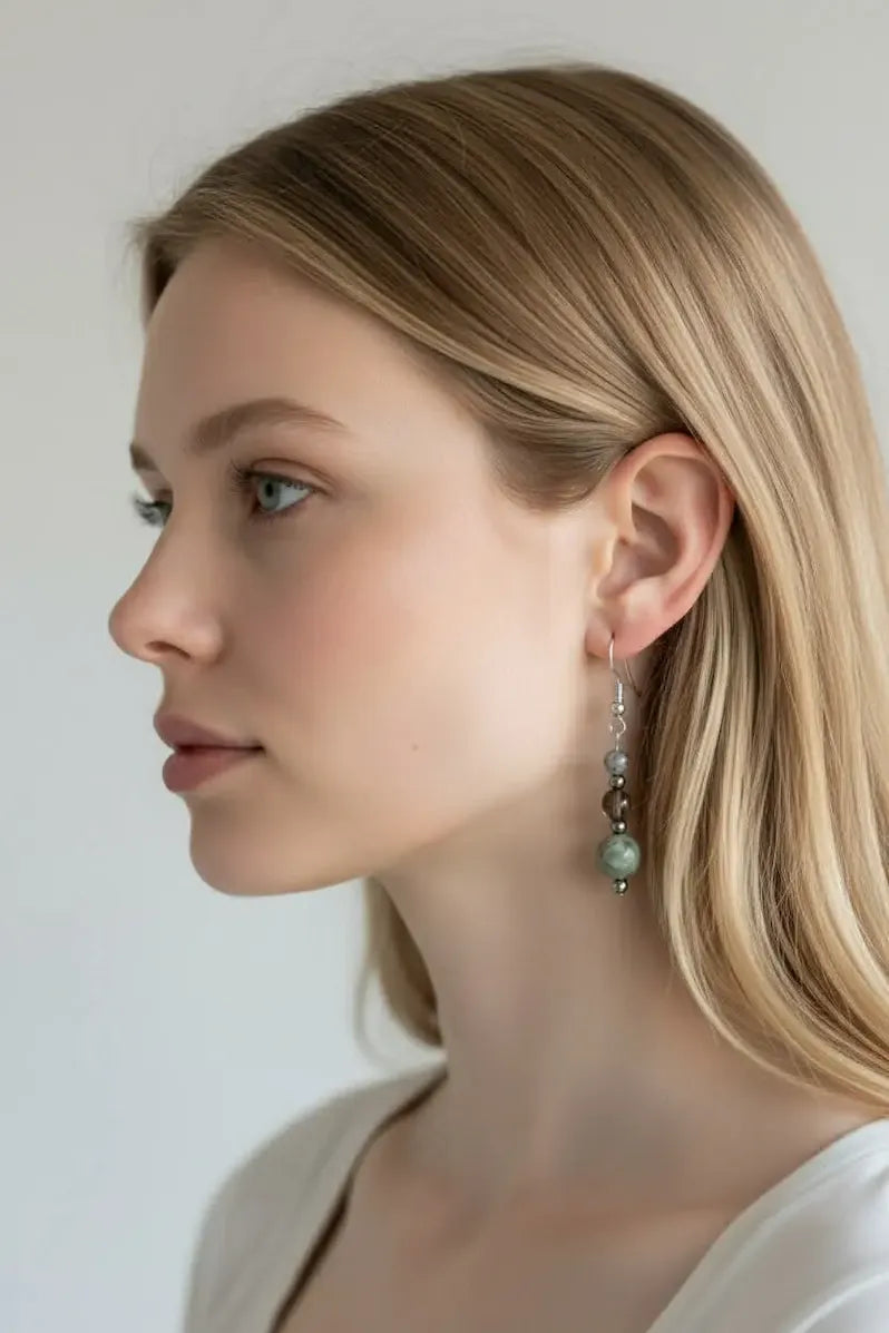Close-up of a woman wearing grounded strength earrings with a plain background.