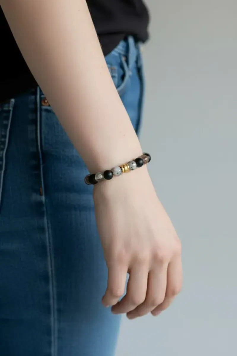 Person wearing a grounded strength bracelet on a blurred background.