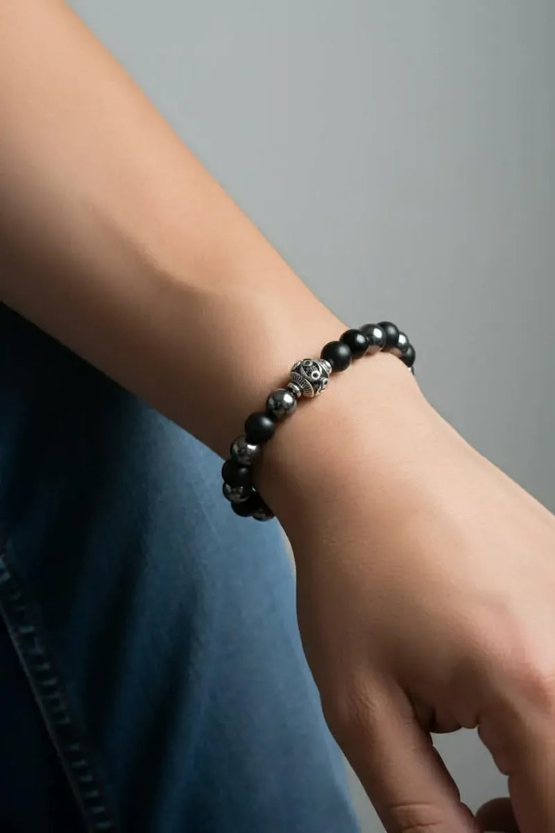 Black hero protection beaded bracelet on a wrist with a neutral background.