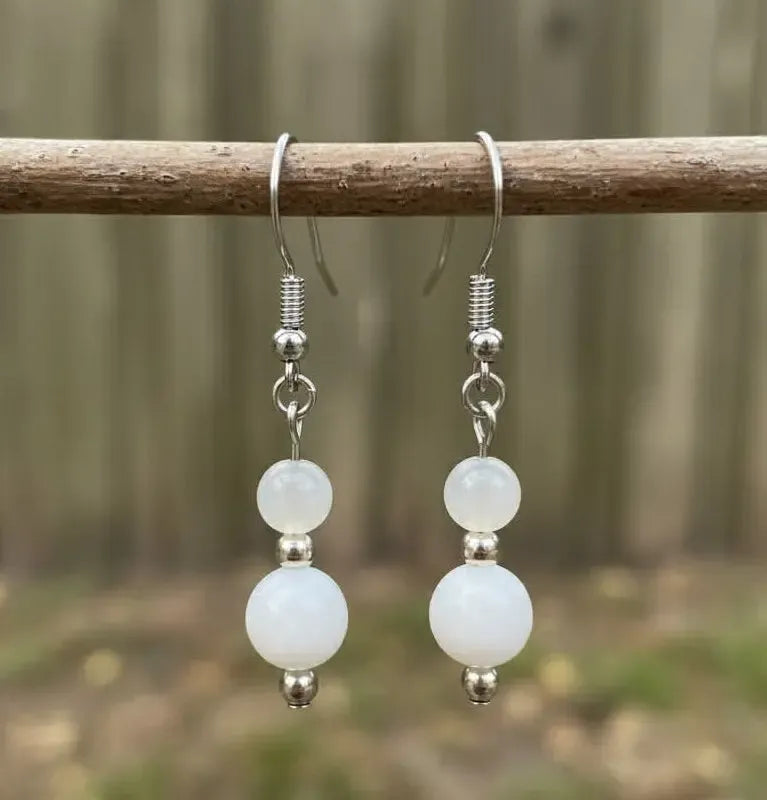 Hero Protection Earrings with moonstone gemstone on silver hook hanging on branch in forest setting.