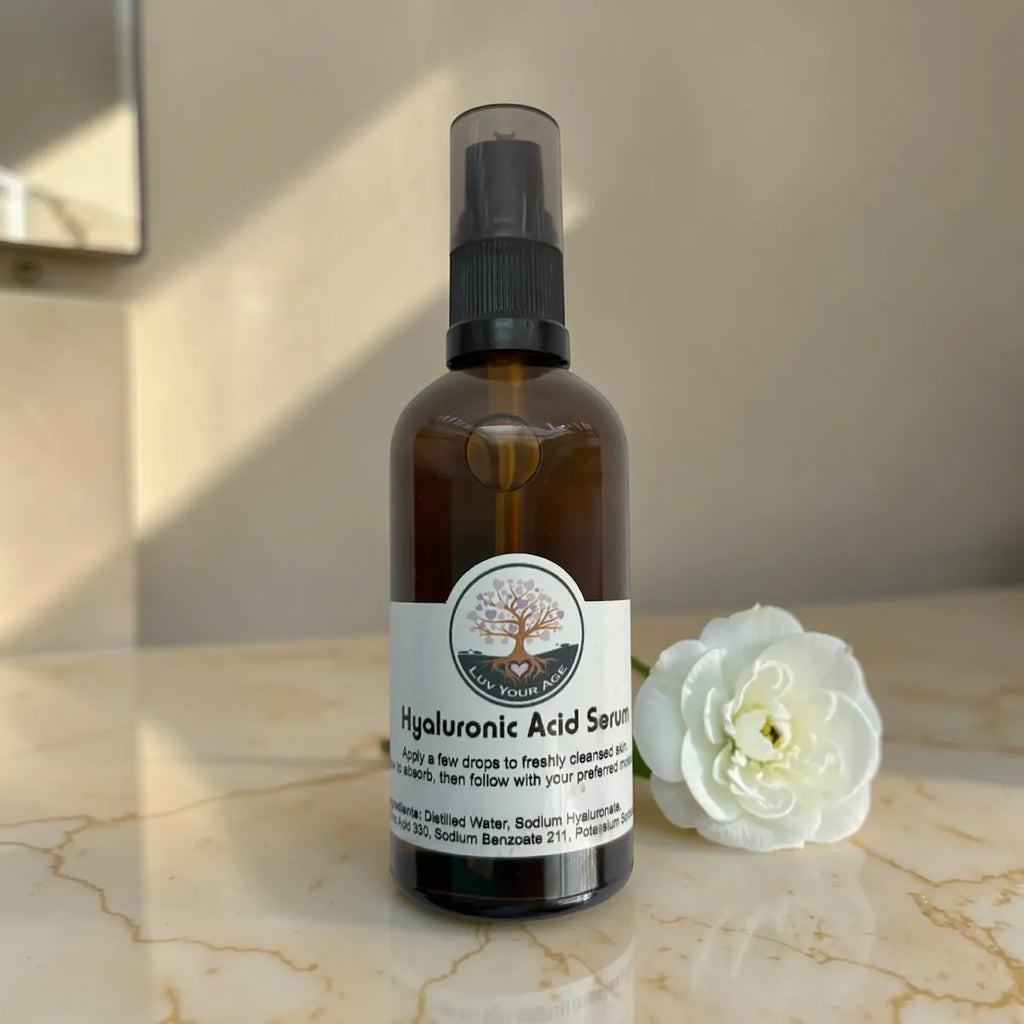 Brown serum bottle with black spray nozzle on a marble surface with a white flower.