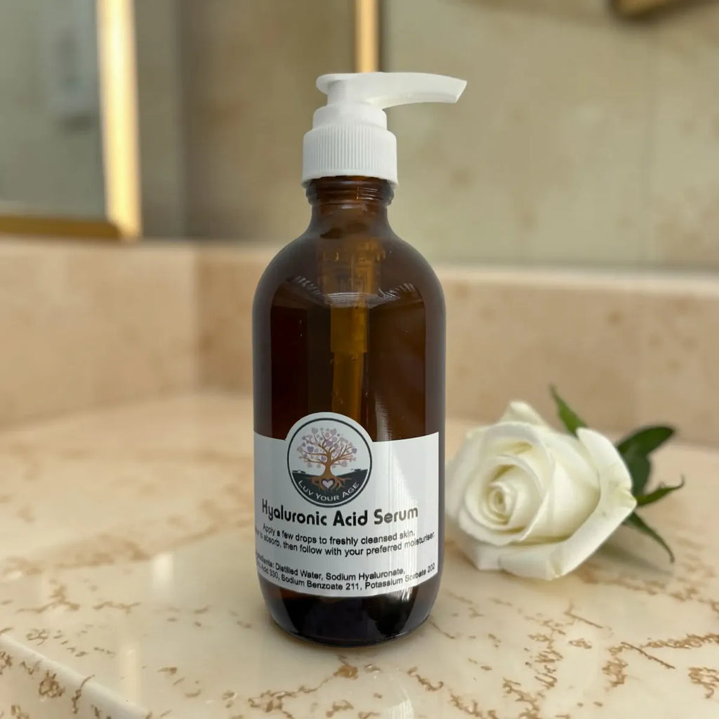 Bottle of Hyaluronic Acid Serum on a bathroom counter with a white rose.