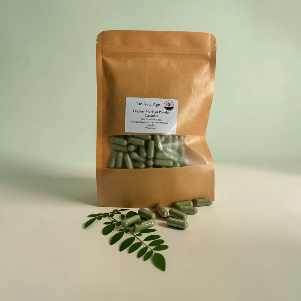 Brown package of organic moringa powder with capsules and leaves on a light background.