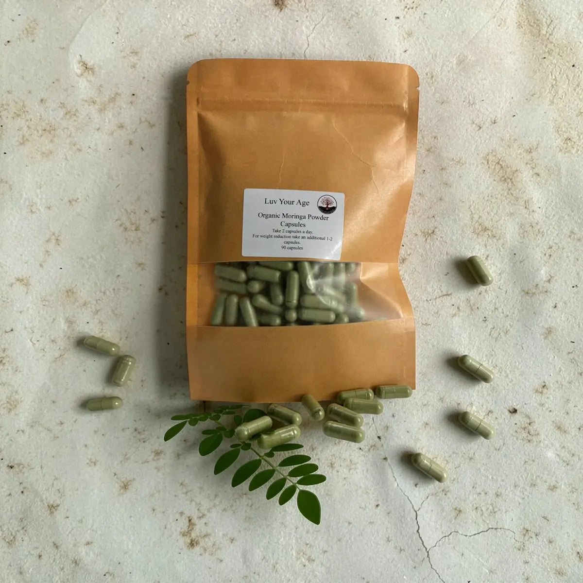Brown package of organic moringa powder with capsules on a textured surface.