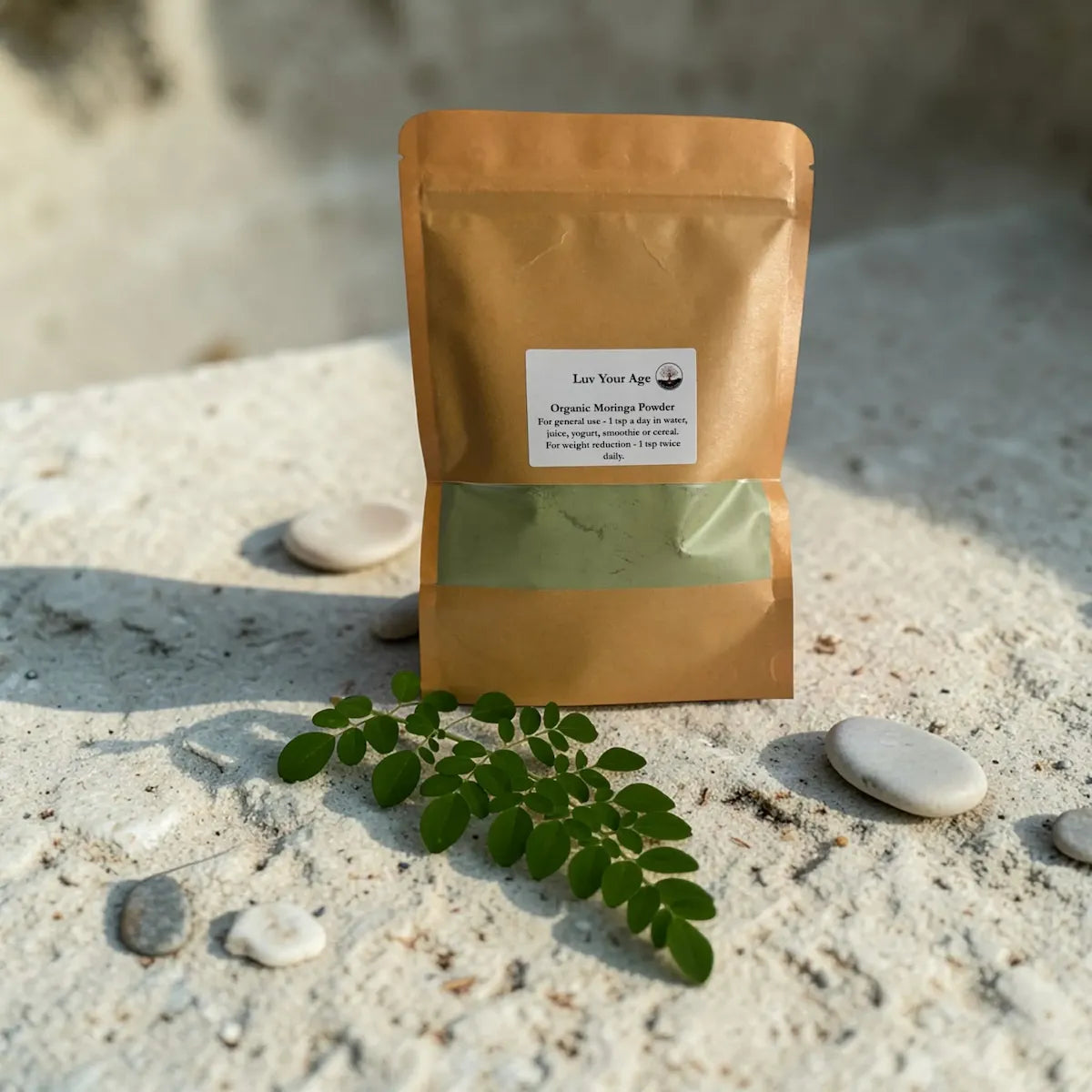 Brown paper package with green powder on a sandy surface with moringa leaves.